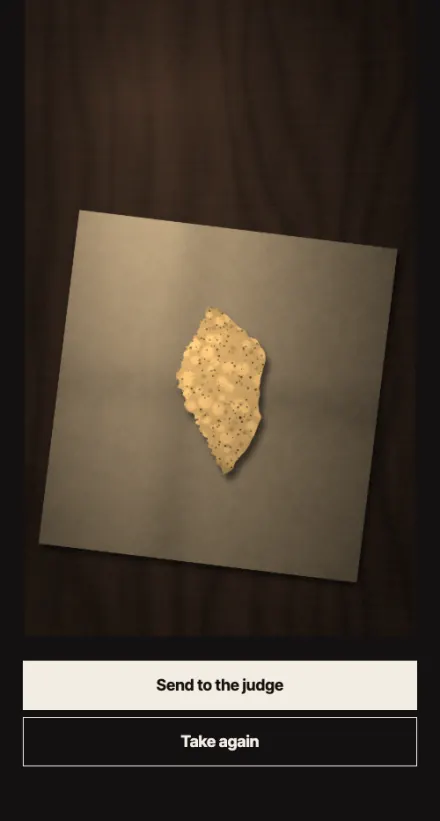 The review screen before the verdict. A broken poppadom lies in the middle of a large pale napkin on a dark table. The buttons read Send to the judge and Take again.